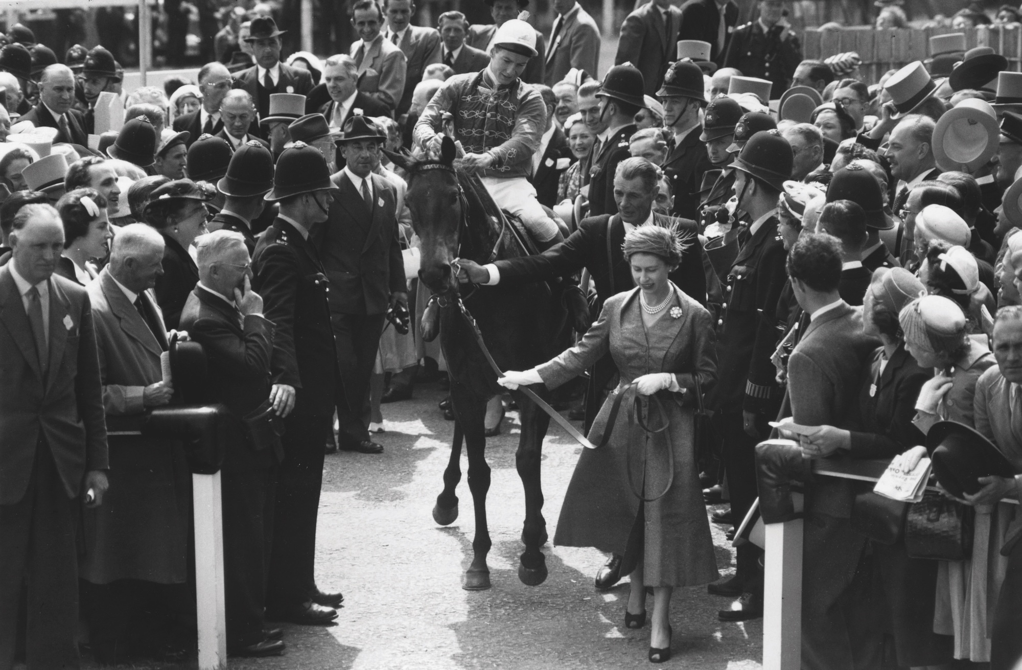 7th June 1957: Queen Elizabeth II of Great Britain leads her horse 'Carrozza' and its jockey Lester Piggott into the winner's enclosure at the Epsom racecourse, Surrey.