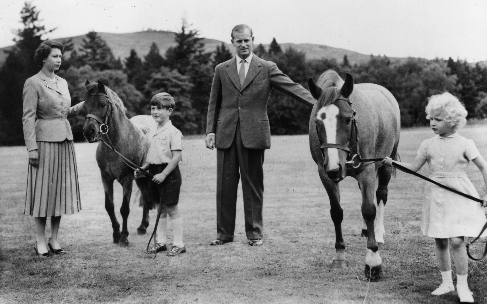 Queen Elizabeth II; Prince Charles (later Prince of Wales); Prince Philip, Duke of Edinburgh and Princess Anne (later Princess Royal) with two ponies in the grounds of Balmoral Castle, Scotland. 