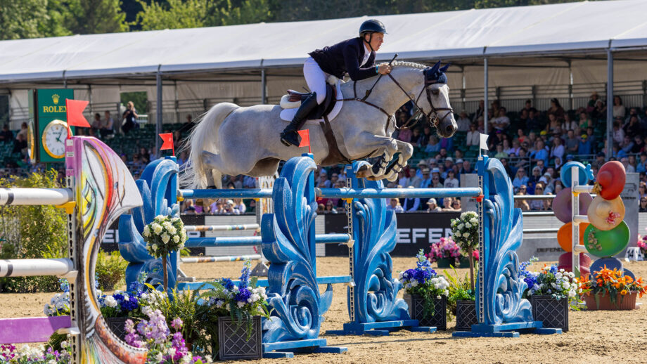 British showjumper Matt Sampson clears a large blue oxer in front of the main arena crowds at Royal Windsor Horse Show.