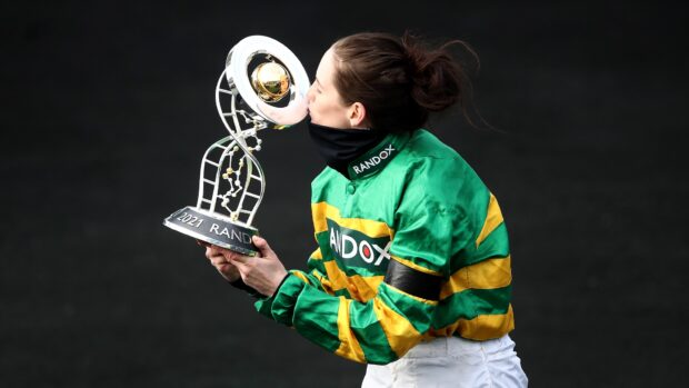 Rachael Blackmore, wearing green and gold silks, kisses the Grand National trophy following her win in 2021 aboard Minella Times.