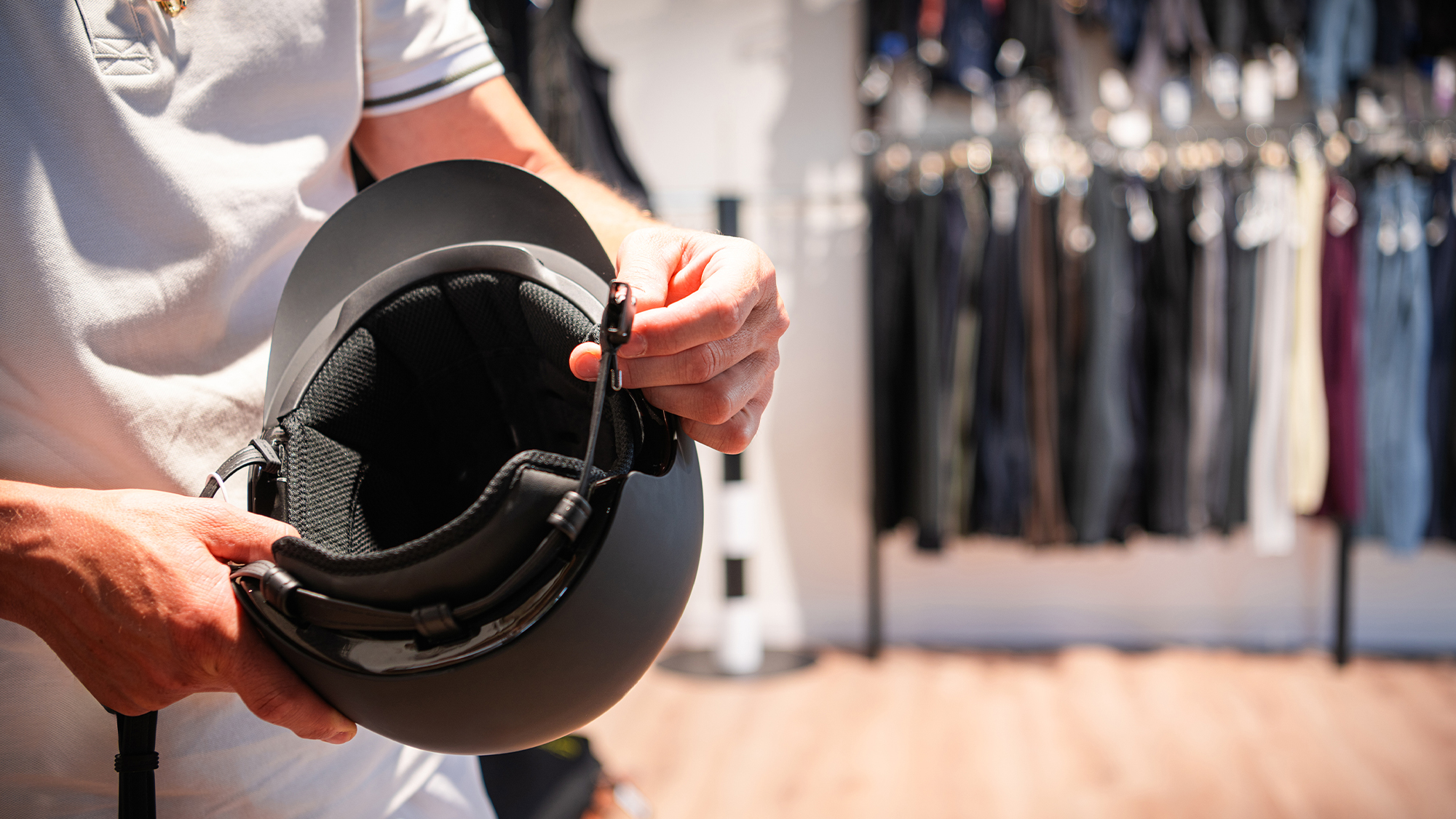 Close up of retail working holding a horse riding helmet in store