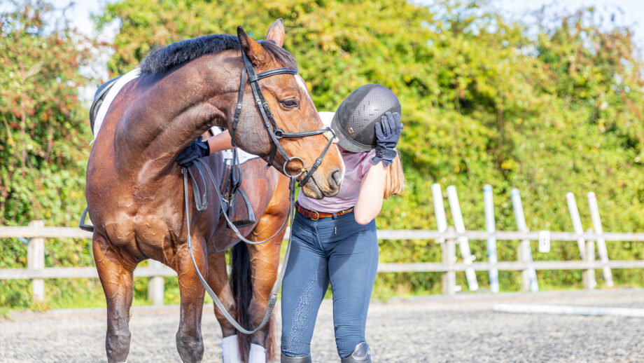 Rider holding horse and clutching head after falling off