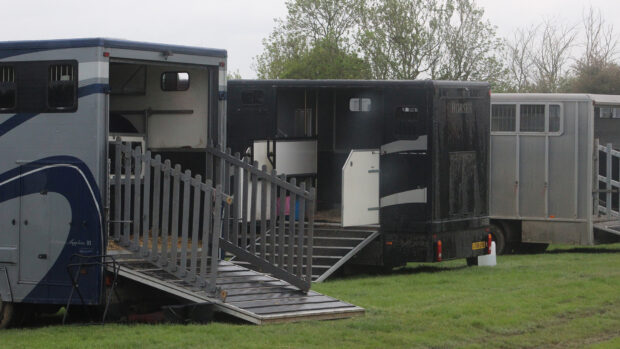Horseboxes parked uo on grass with their ramps open.
