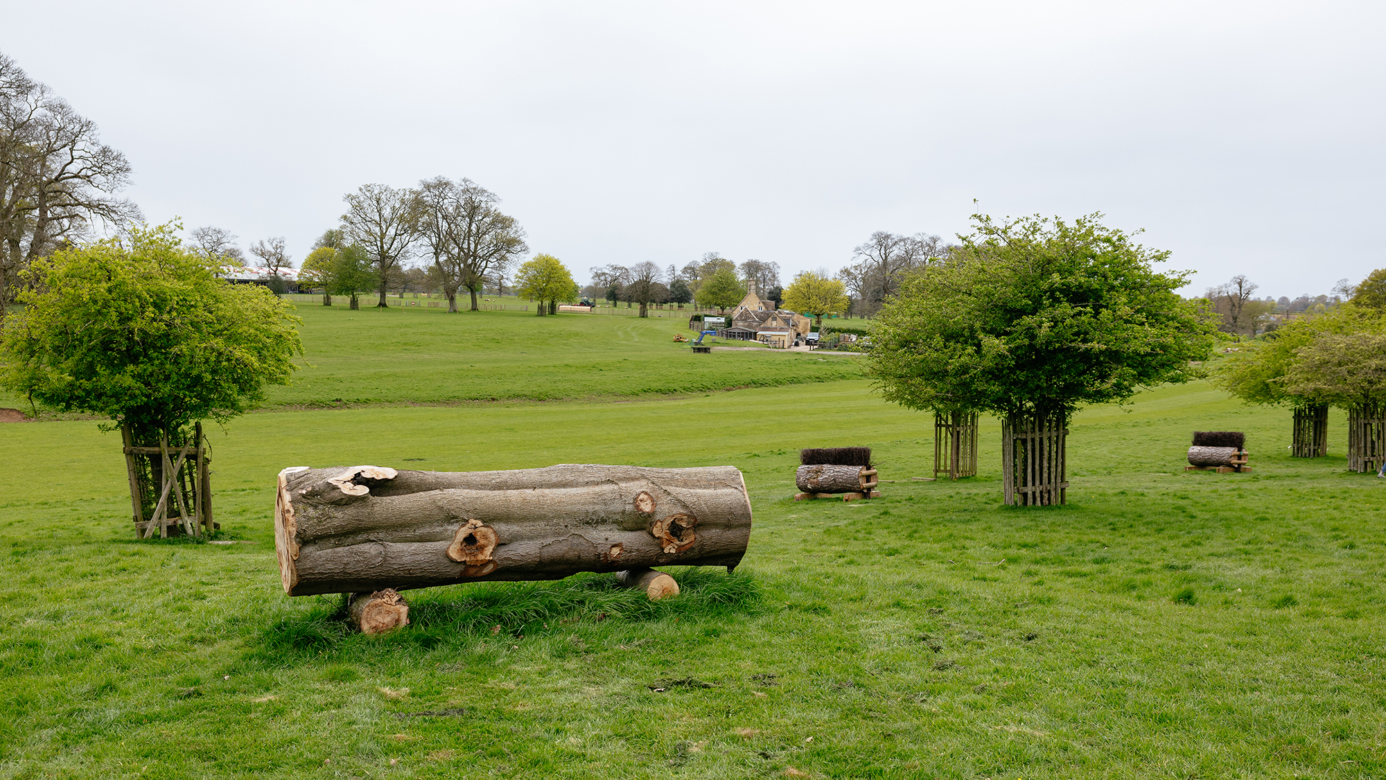 A solid log on the left with the ground falling away on the landing side, with two narrow brush fences on a curving line to the right 