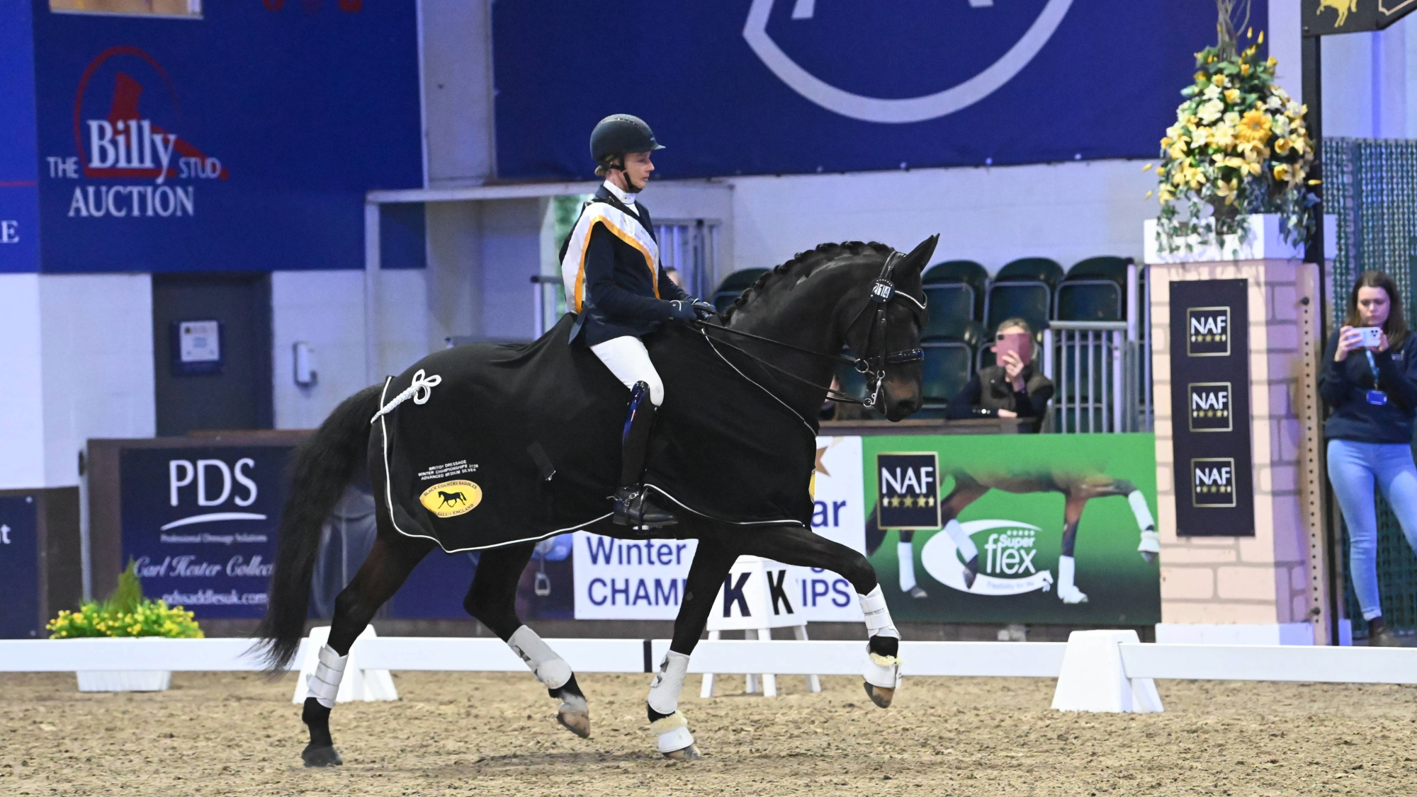 Woman rides a black horse in a black winners rug.