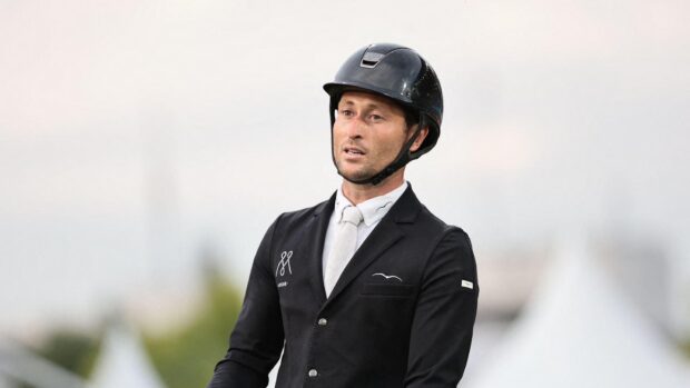 British showjumper Adrian Whiteway wearing a black show jacket and riding hat with a white shirt and tie.