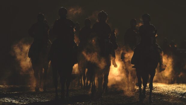 Racehorses return from exercising as the sun rises above the trees on