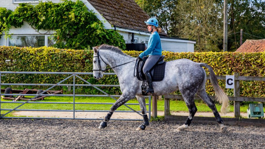 Rider cantering in arena just past a marker