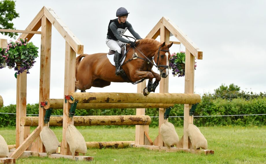 Rider Ollie Thompson jumping a cross-country fence with a chestnut horse