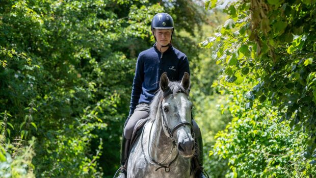 Rider Ollie Thompson hacking out with a dapple grey horse