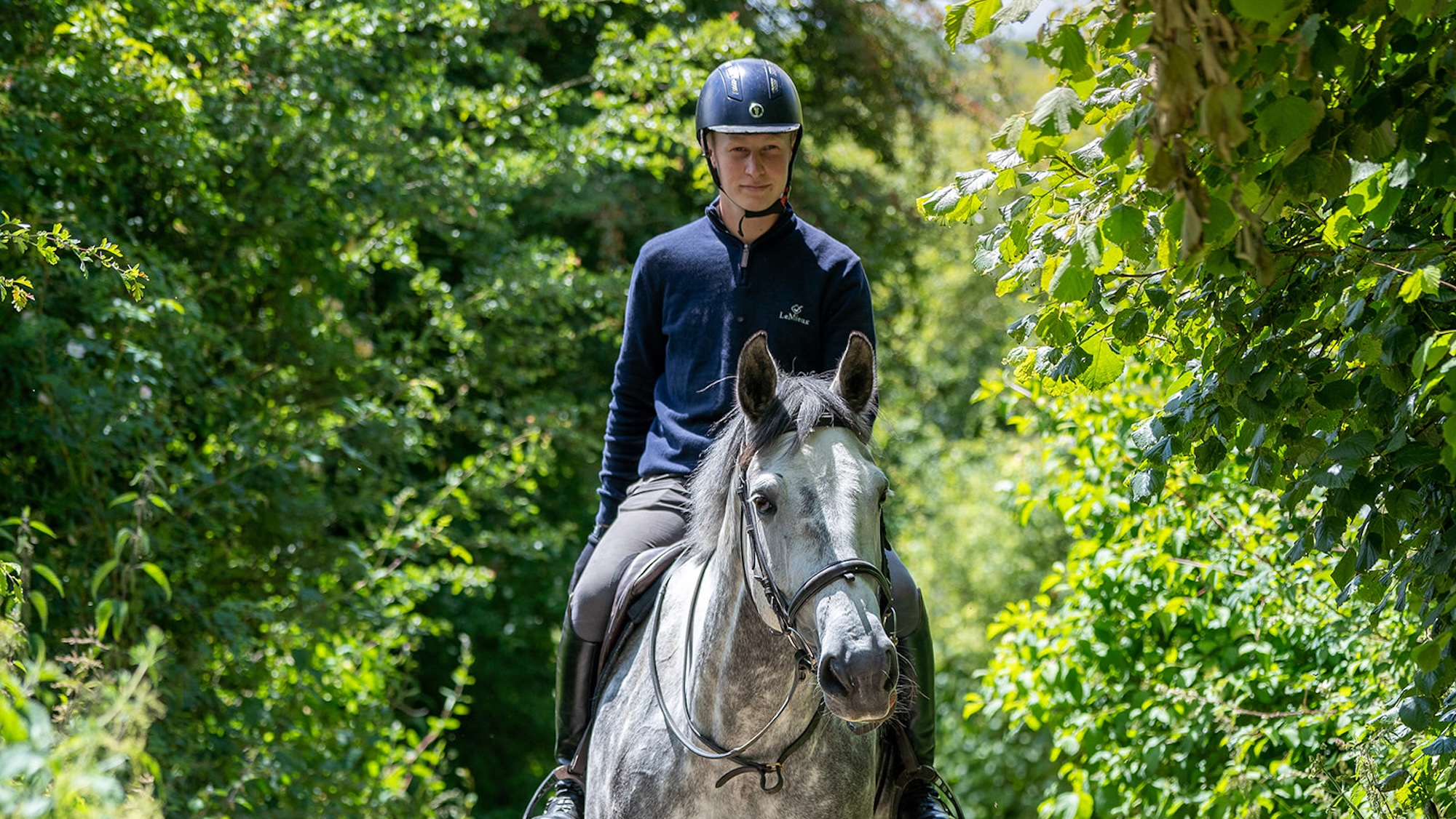 Rider Ollie Thompson hacking out with a dapple grey horse