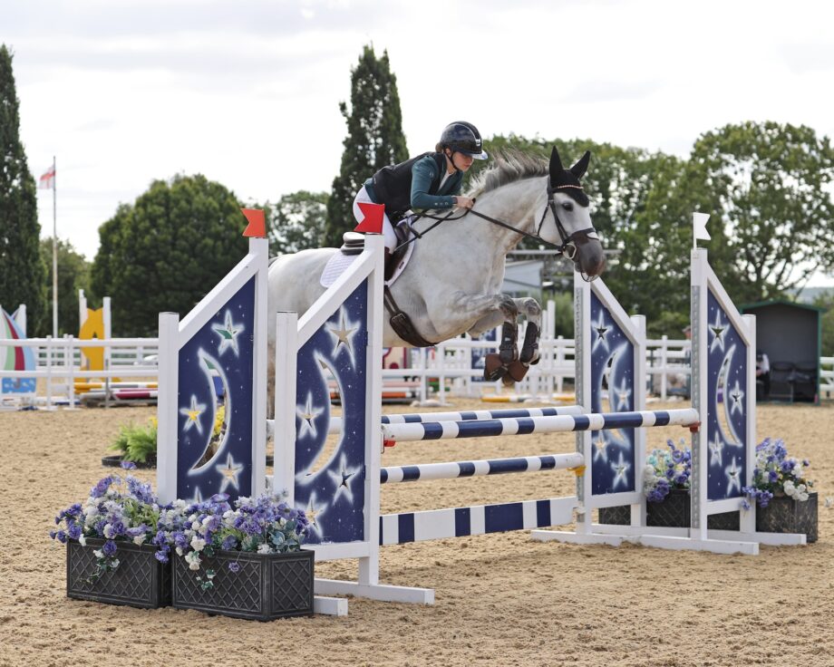A rider and a grey horse jumping a fence at the BS national championships