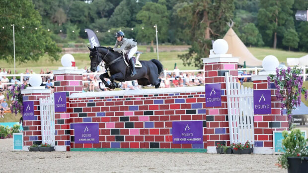 A black horse clears a big red puissance wall at Bolesworth International horse show