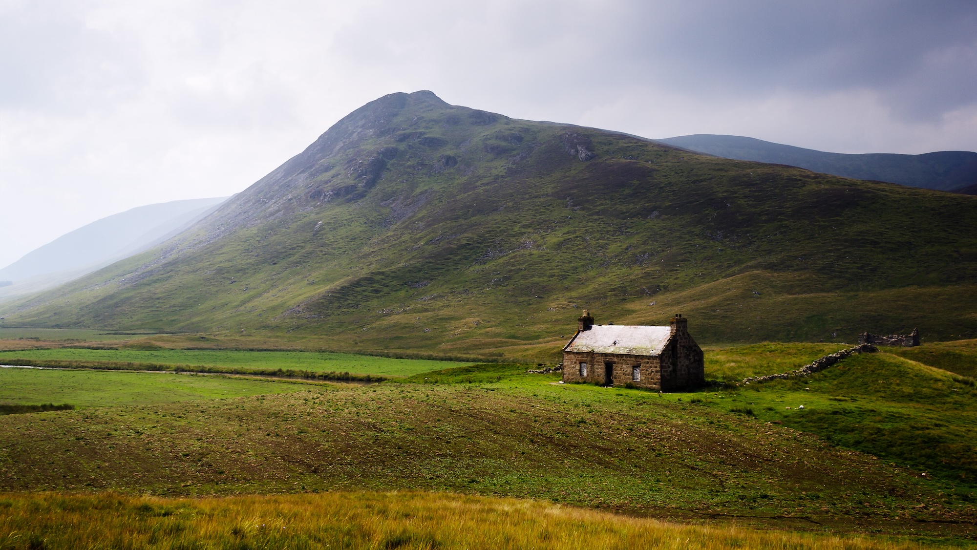 Croft house in scotland, with backdrop of mountain