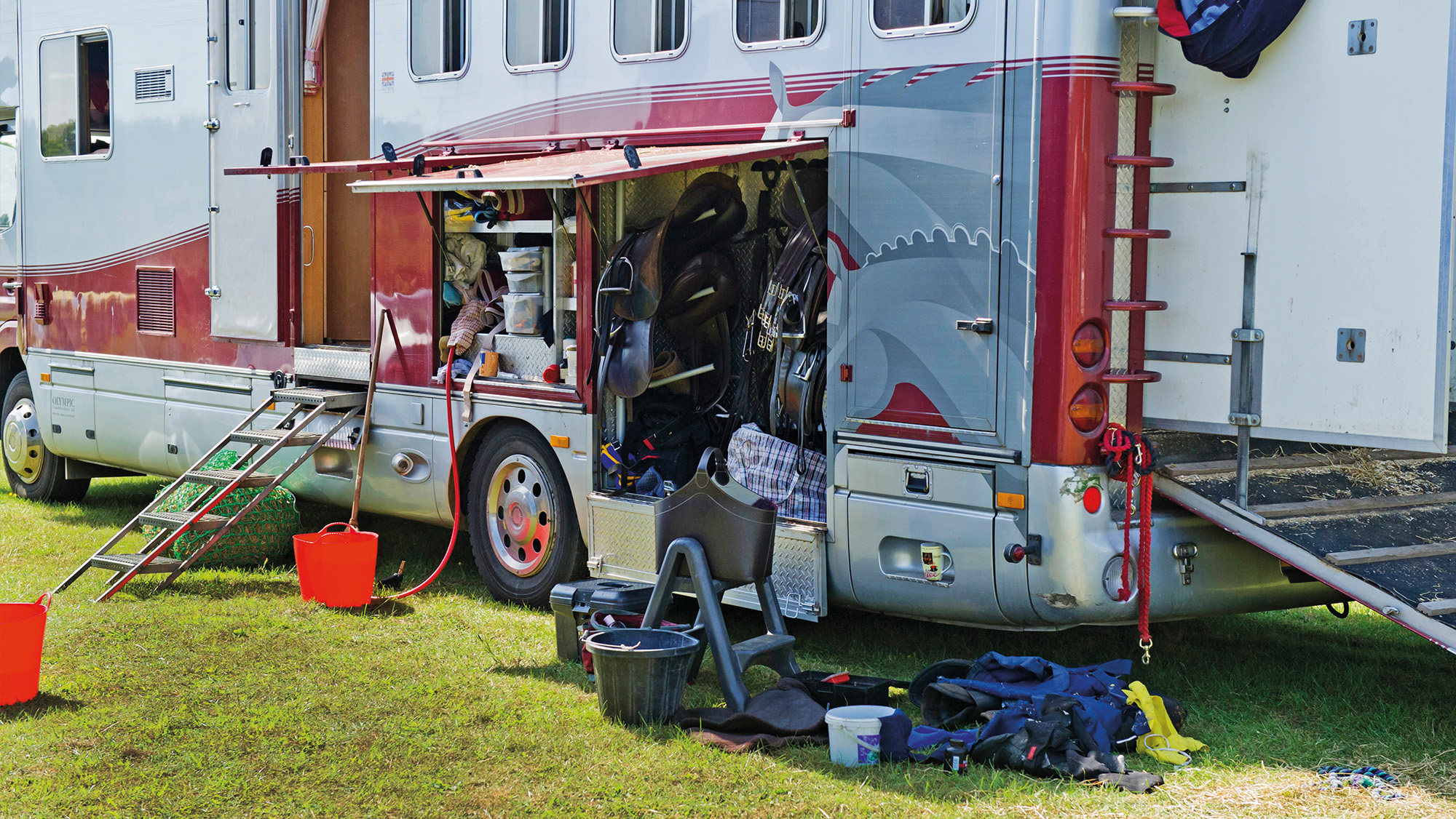 Lorry in lorry park at competition with horse and rider kit around on the floor and in tack locker