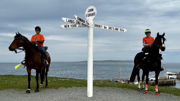 A rider and horse on each side of the John O'Groats sign