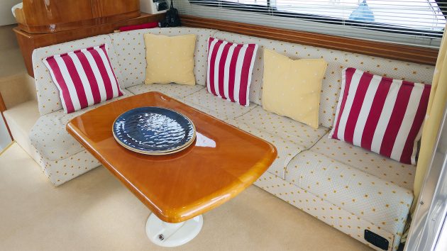 A beige-cream sofa area with stripy cushions. In front, there is a cherry wood rectangular table.