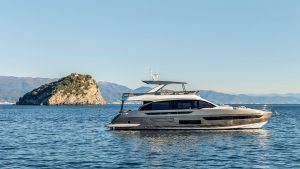 Side profile of the Azimut on the water with a medium sized rock behind it. The sun is shining and sky is clear.