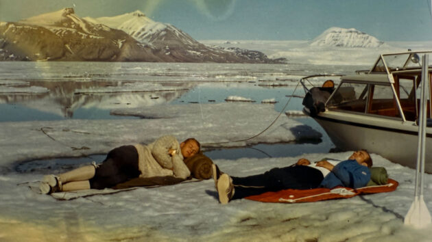In the Arctic, two people lying on the ice