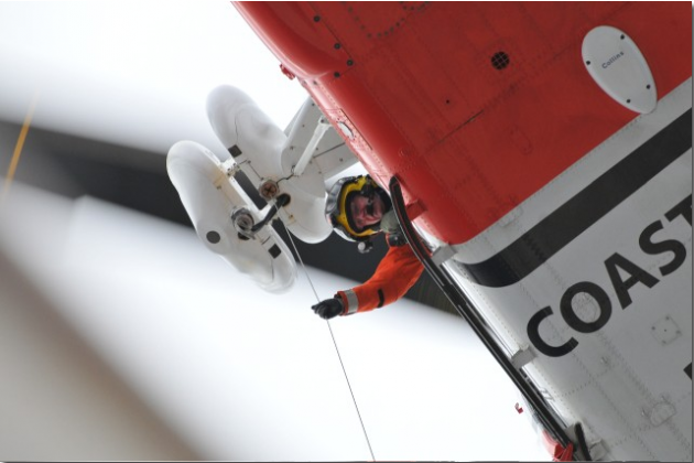 Coastguard helicopter winch man lowering cable during rescue