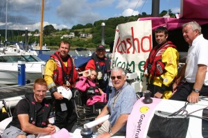 Peter Goldstraw from The Rotary Club of Dartmouth (centre) prepares to present Natasha with a cheque as she is welcomed to Dartmouth by the RNLI Dart Lifeboat and Dart Sailability. Dad Gary and coach Phil Devereux watch on