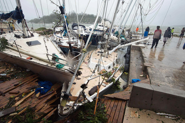 Local residents look at damaged boats against a jetty in Port Vila. Picture credit: UNICEF Pacific