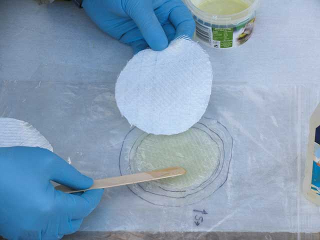13: Once wetted, place the second smallest circle directly on top, staying within the guidelines, and wet out. Just keep going like this until all the circles have been laid one on top of the other. The biggest one will be last, and will be pressed against the hole itself.