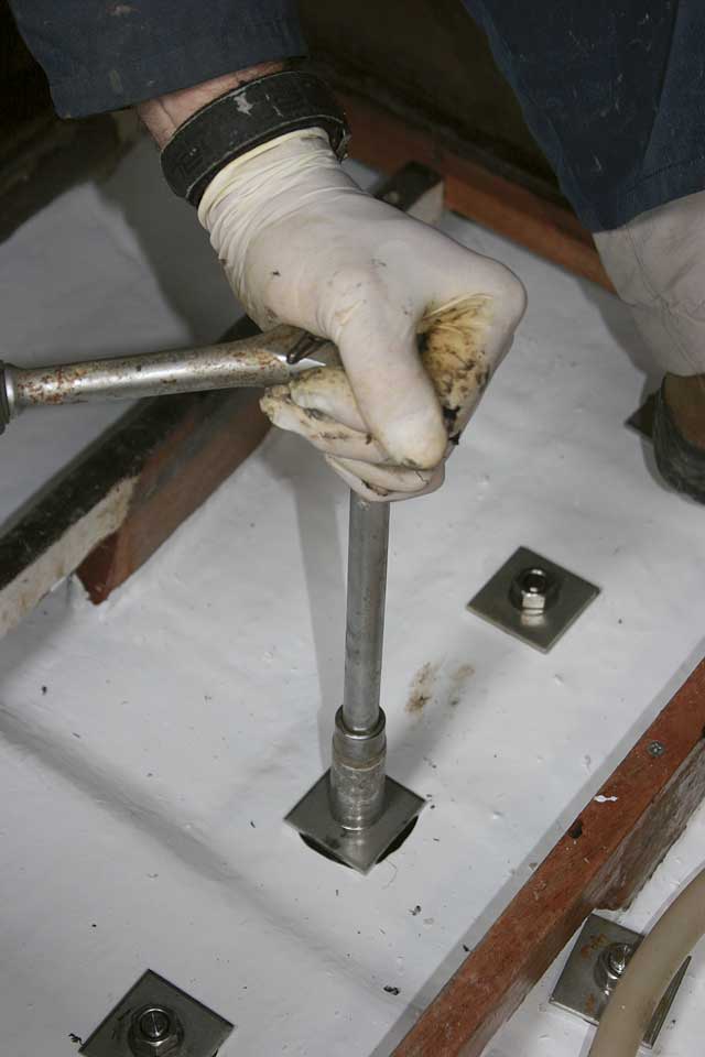 5: With the studs protuding up through the inside of the hull Andy applies Sikaflex around the stud holes to stop bilge water penetrating the lay-up. He then inserts the plates, washers and nuts, tightening each nut a little at a time
