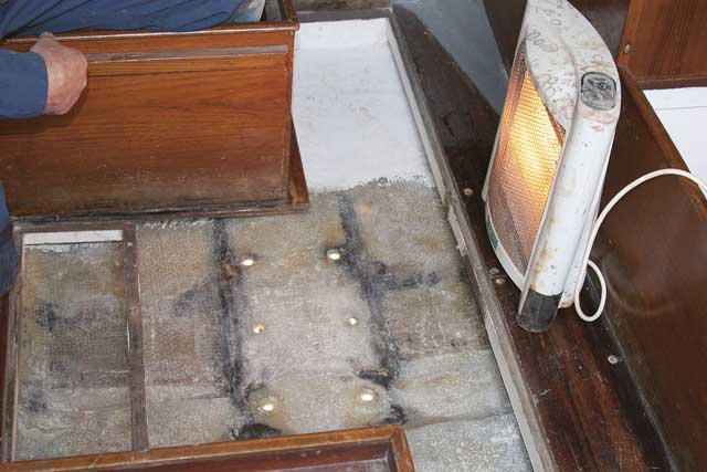 4: Andy removes the plywood stiffeners from the sole and cleans away the rust. The black marks are where water has got in. He glasses in the bolt holes with chopped strand mat (CSM) and resin (see STEP 2) then leaves the repair to dry for a few days