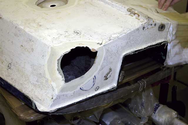 1: The corner of this dinghy has been taken off by a collision, but being a sealed buoyancy tank, it was impossible to access from the inside. Somehow, we had to get a backing plate behind the hole so we could build up against it. If an undamaged part of the boat matches the damaged area, it can be used as a mould for just such a backing plate. Firstly, the outer surface is cut back to make a shallow depression. The inside edges of the hole are also abraded and wiped with epoxy.