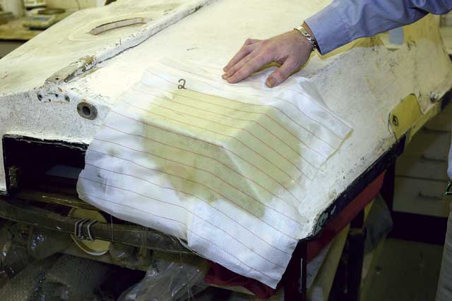 2: The undamaged starboard corner was a close enough match to make a mould from. (Better still, a dinghy from the same class could be used for a perfect mould.) The corner was coated with release wax, and then a layer of reinforcing cloth was laid over the top. It was taped down to create the shape, and then coated with activated epoxy. A sheet of peel-ply is placed over the top to give a roughened surface.