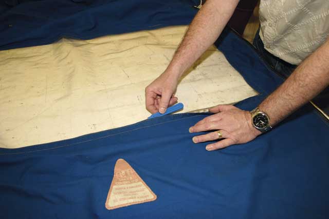 2: With the cover laid outside-up on the table, Alan begins by running his stitch-cutter along the window’s inner edge seam, in order to remove all the threads.