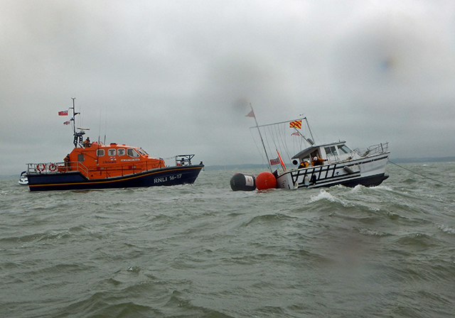 The heavily listing catamaran, with Bembridge lifeboat nearby. Credit: RNLI/George Chastney