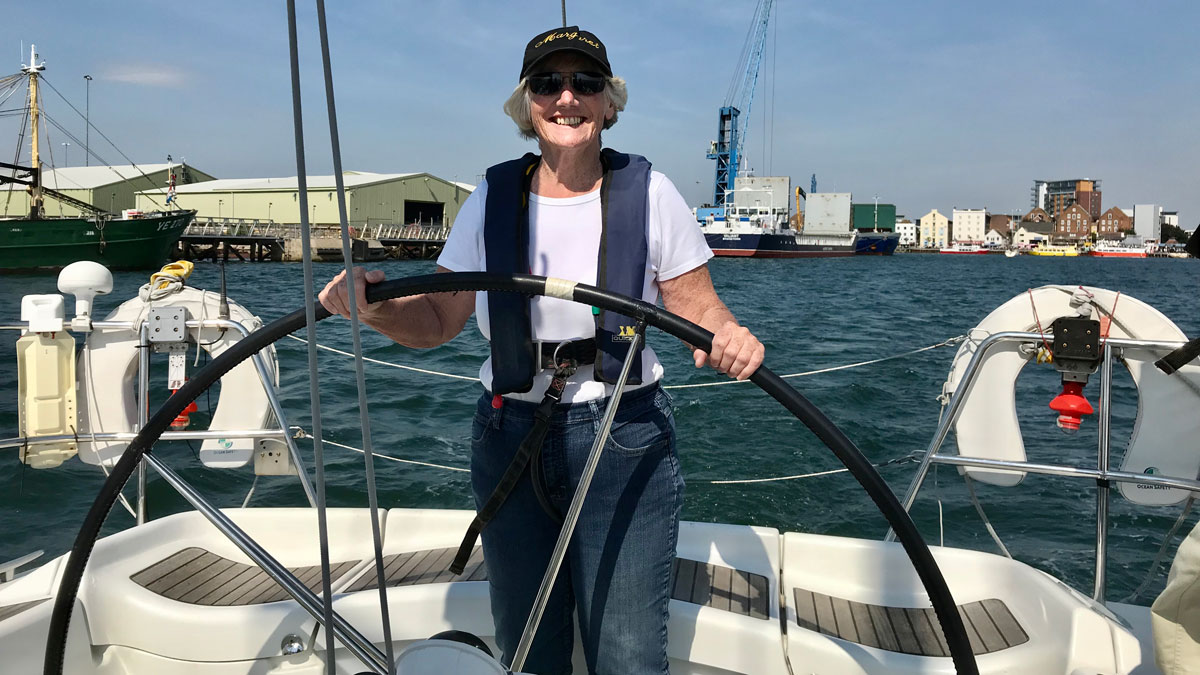 A woman wearing a lifejacket at the helm of a boat