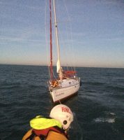 The damaged vessel Joie de Vivre is taken in tow by Llandudno RNLI lifeboat as dusk approaches. Credit: RNLI/Llandudno