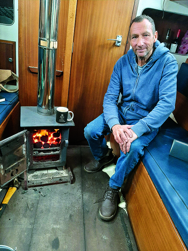 A man sitting next to a solid fuel heater on a boat