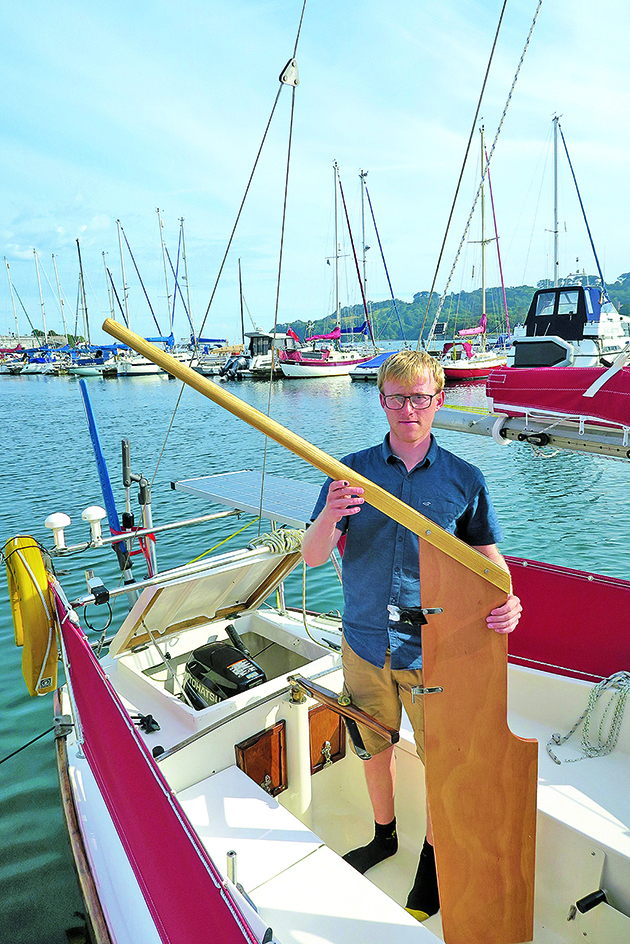 A man holding an emergency rudder on a boat