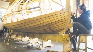 A woman wooden boat building in a shed