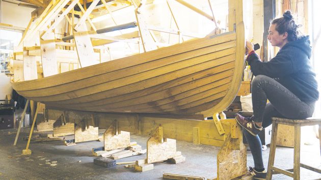 A woman wooden boat building in a shed
