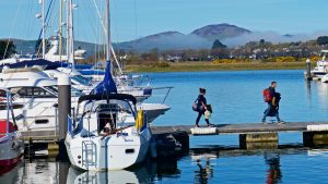 Two people walking along a pontoon as a marina