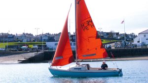 A hunter 19 with red sails and a light blue hull sailings