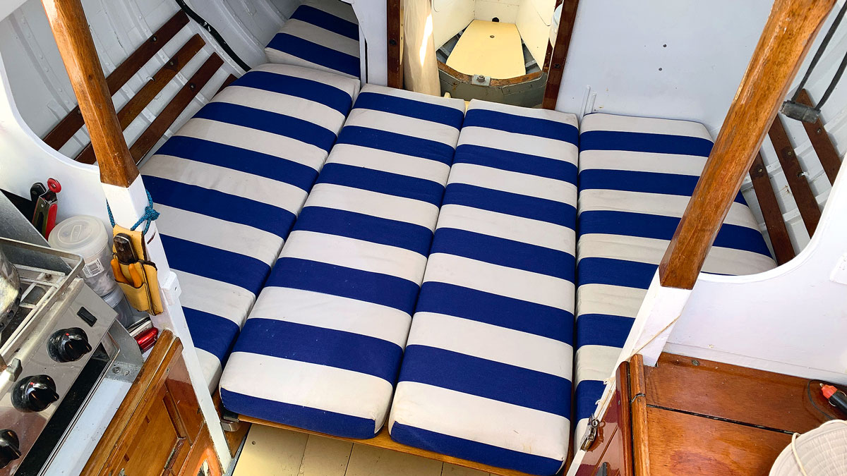 A boat berth covered in blue and white fabric on a boat