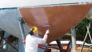 A man overcoating Coppercoat antifouling on a boat hull