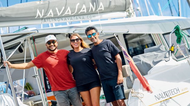 Three people smiling on the deck of a catamaran