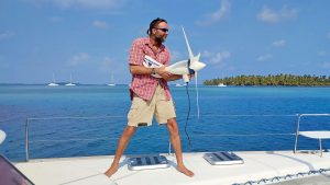 A man holding a boat wind generator on the deck of a boat