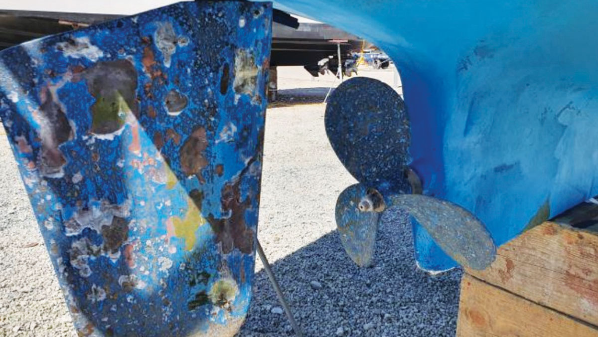 A rudder and prop on a boat with a gap between both of them