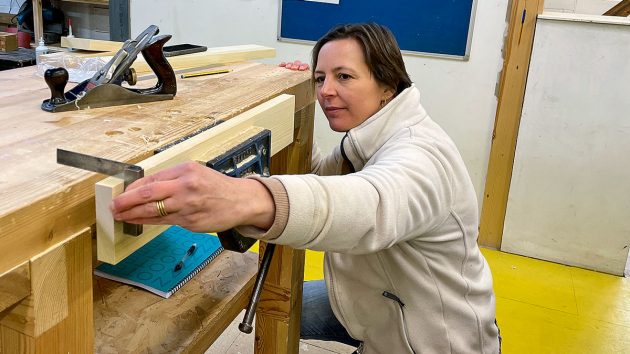 A woman using a set square at a work bench