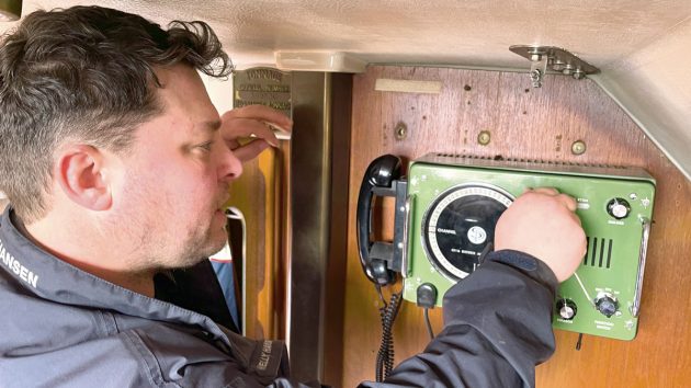 A man installing a restored Sailor radio on a boat