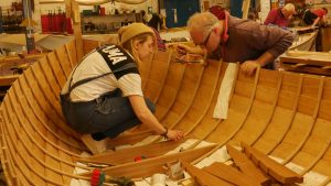 A woman and a man building a boat at the Boat Building Academy