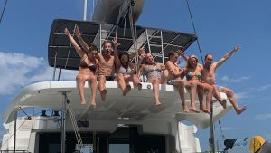 People sitting on the top of a hard bimini on a catamaran during a PlainSailing.com specialises in charters in the Mediterranean, UK and the Caribbean. Credit: PlainSailing.com charter